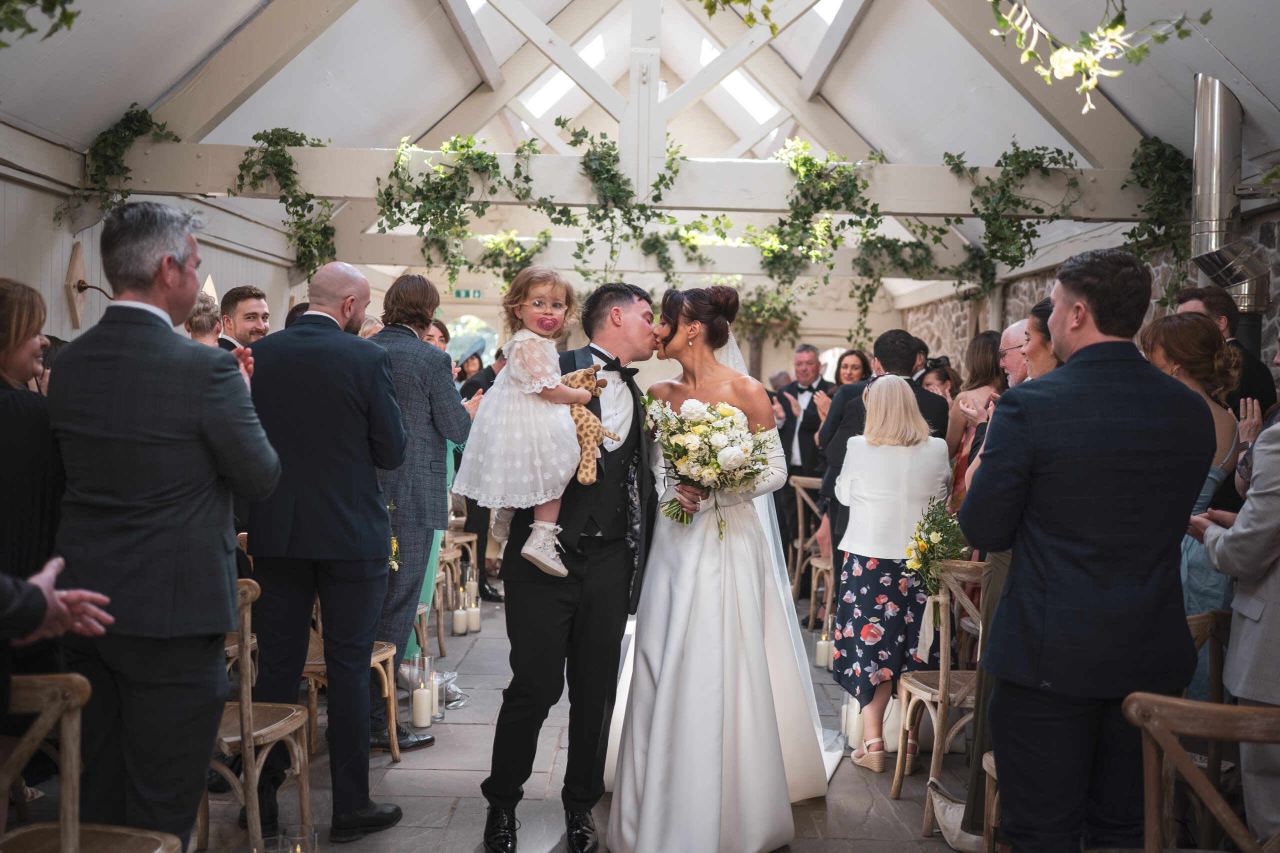 The newlyweds and their little girl walking back out of their ceremony.